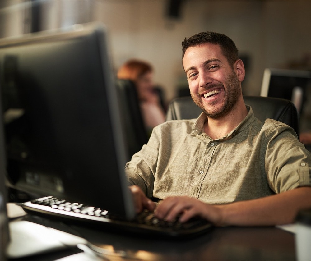 Profissional do time da Contabilidade.com sorrindo enquanto trabalha no computador